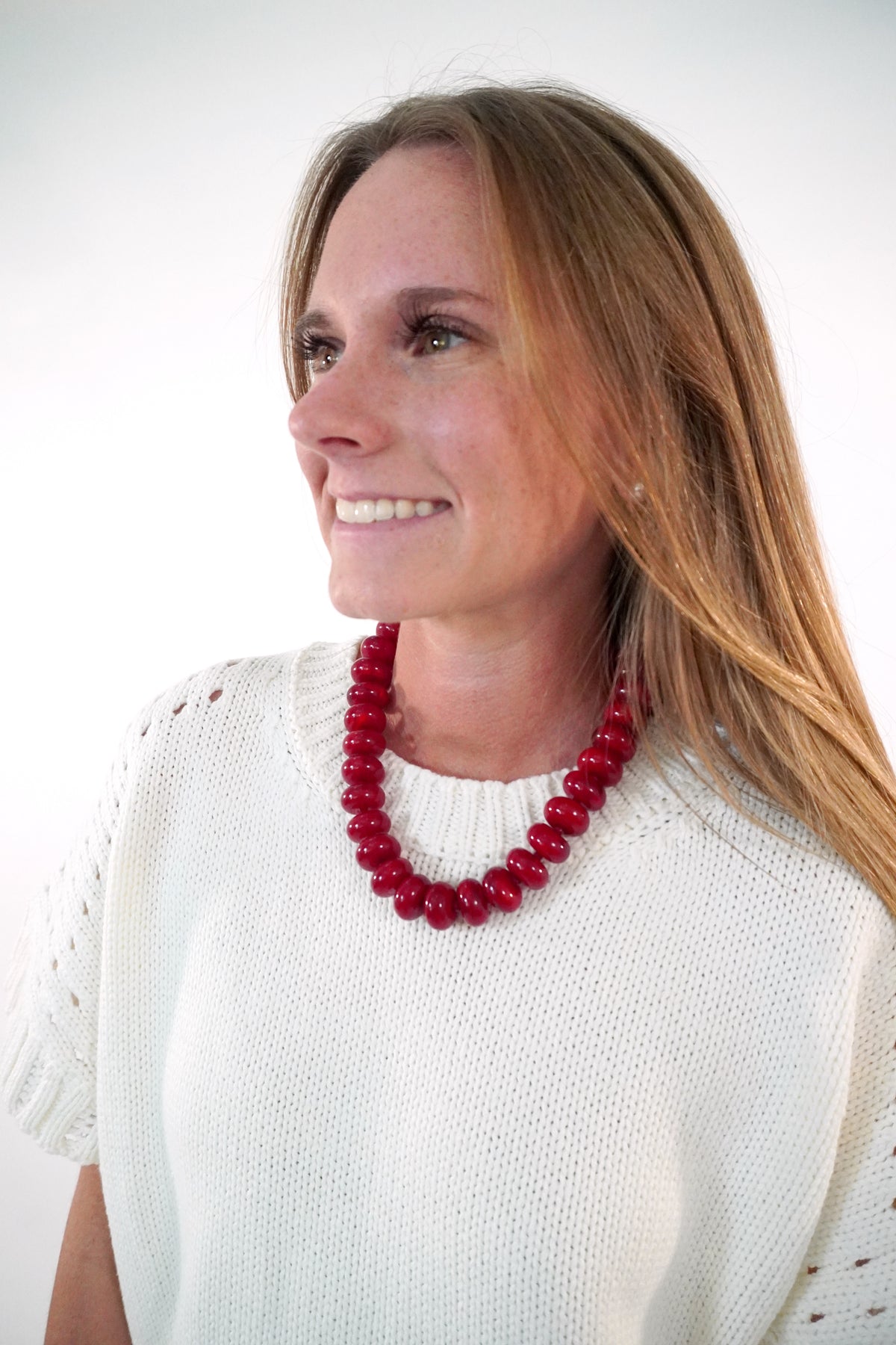 Chunky cherry red marbled beaded collar necklace worn over a cream knit