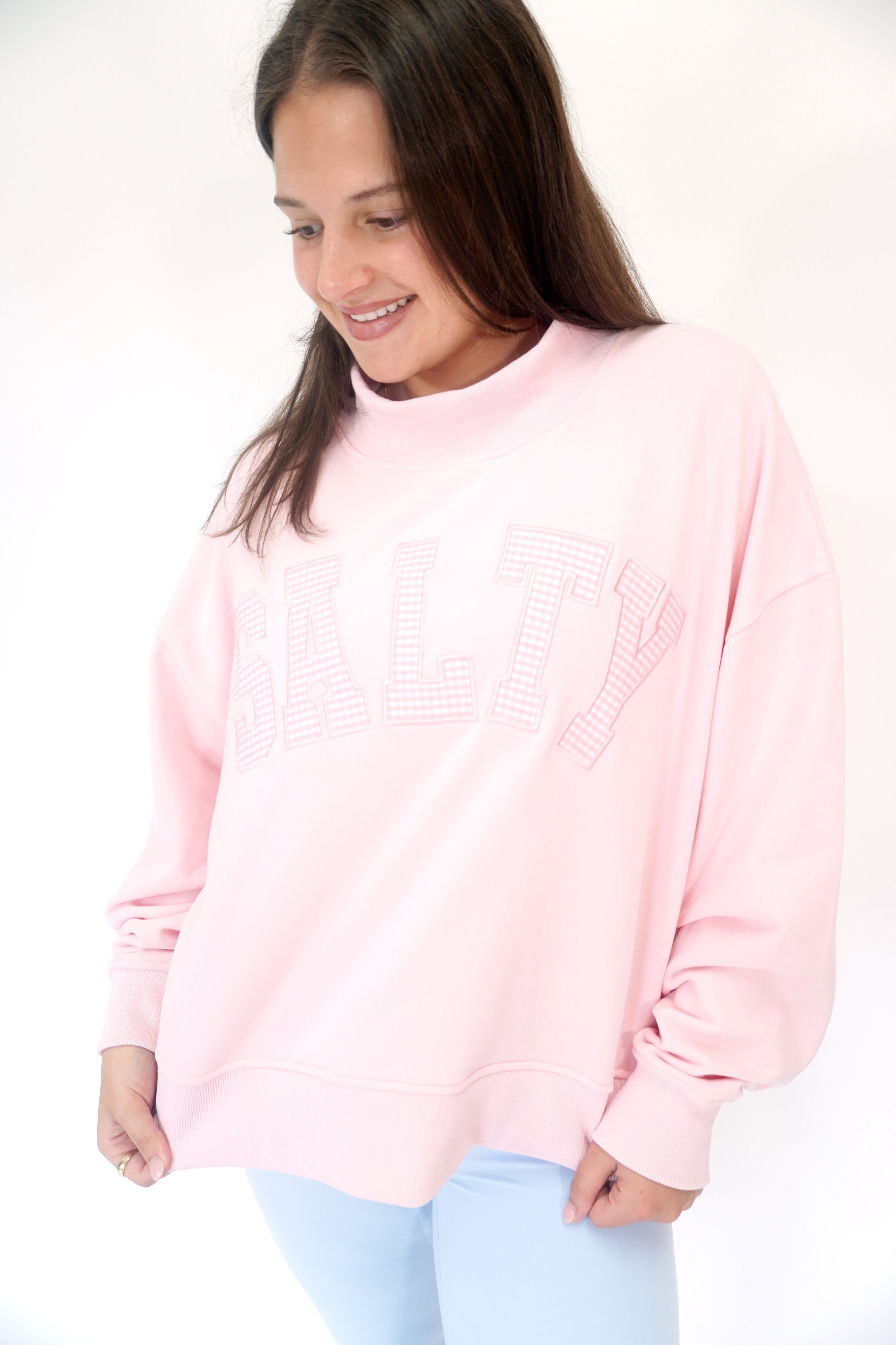 Soft pink mock neck sweatshirt with SALTY graphic lettering and relaxed oversized fit.
