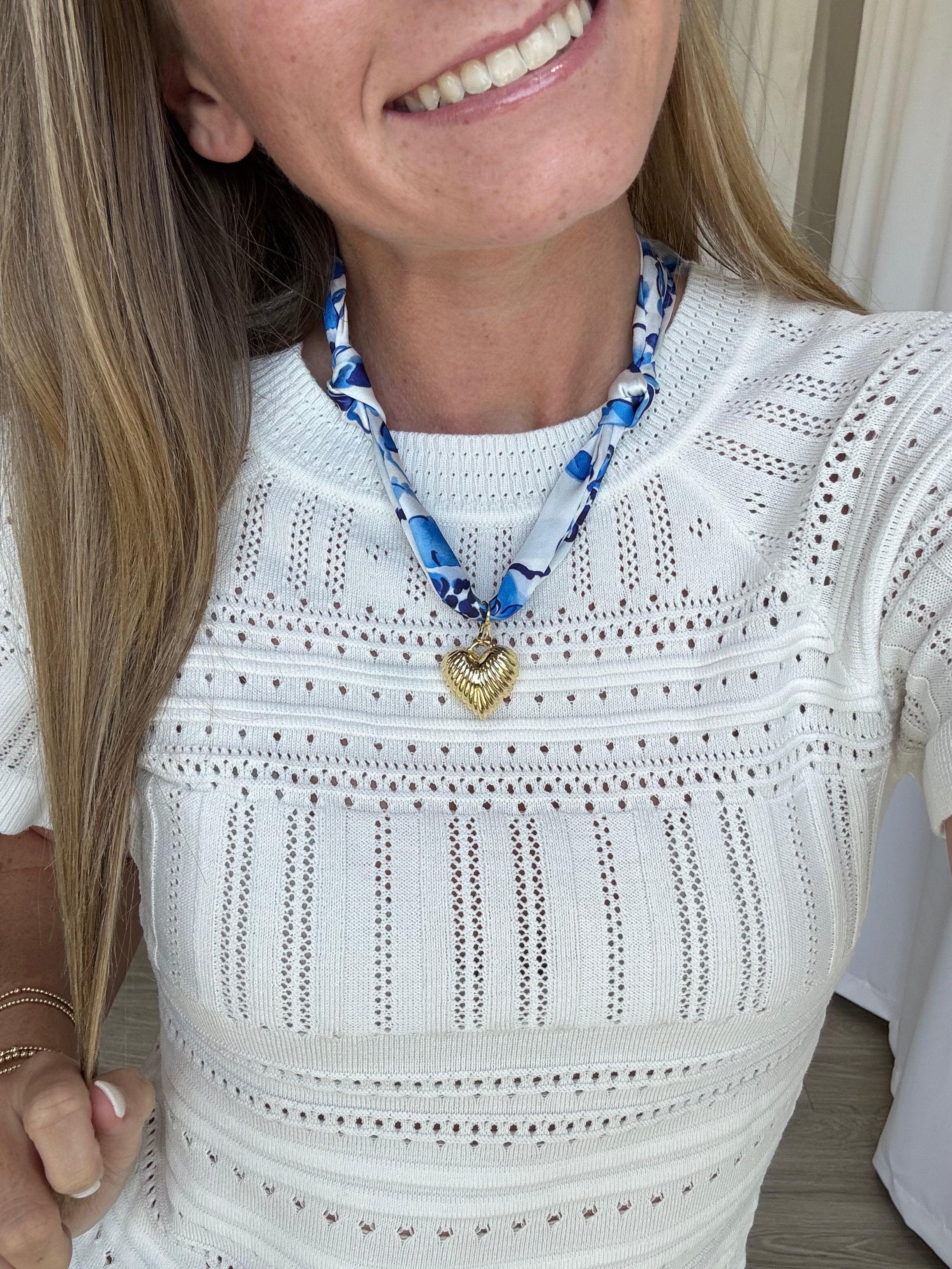 Orange and blue scarf necklace with a gold heart pendant, styled around the neck for a chic, vibrant look