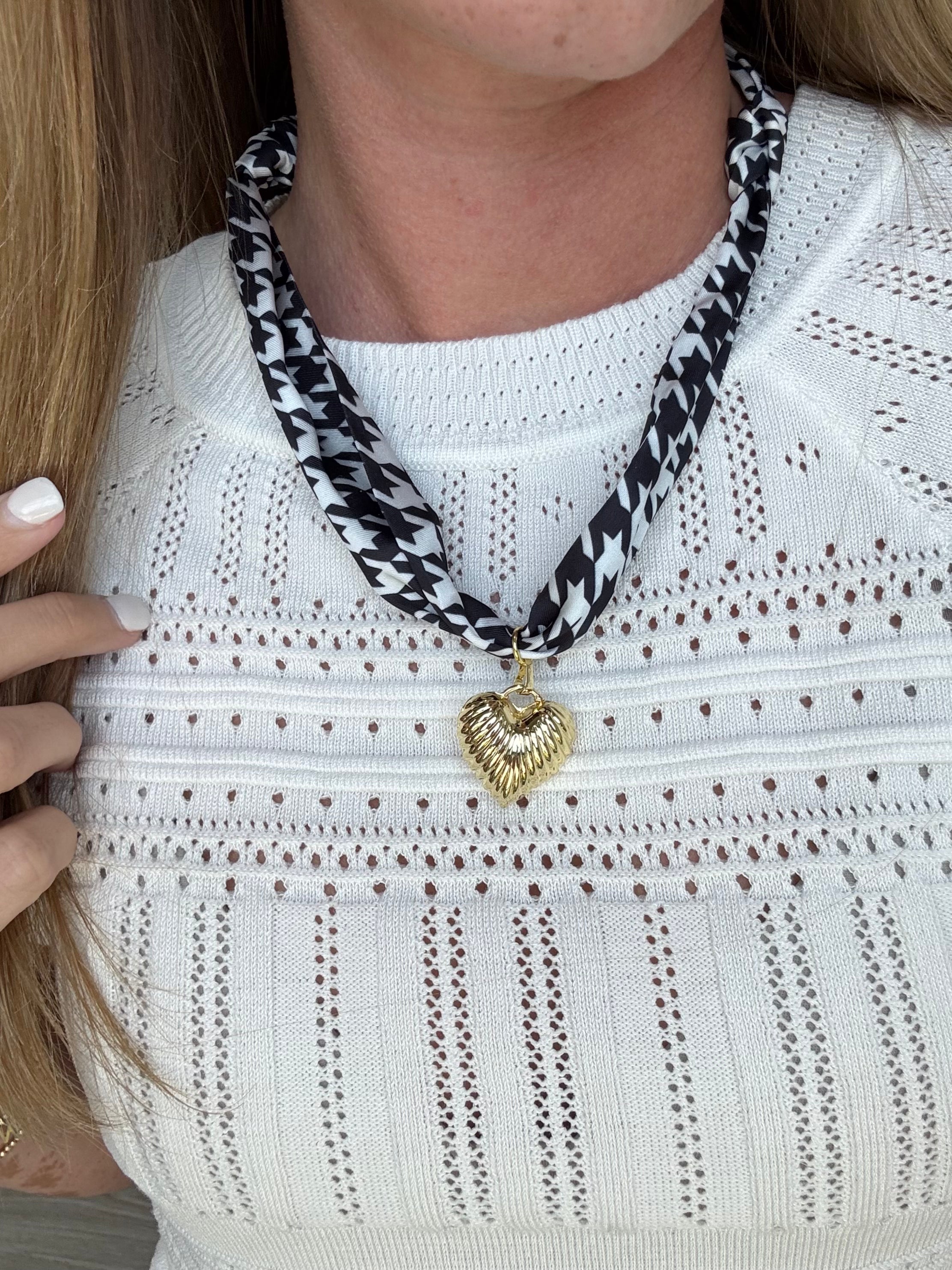 Fashion scarf in black and white houndstooth pattern with a delicate gold heart charm, perfect for elevating any outfit