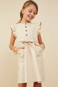 Young girl wearing a cream dress with buttons on a beige background