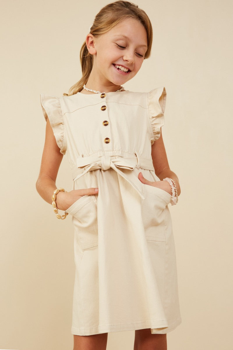 Young girl wearing a cream dress with buttons on a beige background