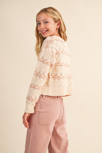 Close-up detail of cream open-knit fabric with blush stripes on tween sweater