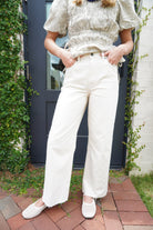 Ivory high-rise wide leg jeans with a cropped raw hem and classic five-pocket design.