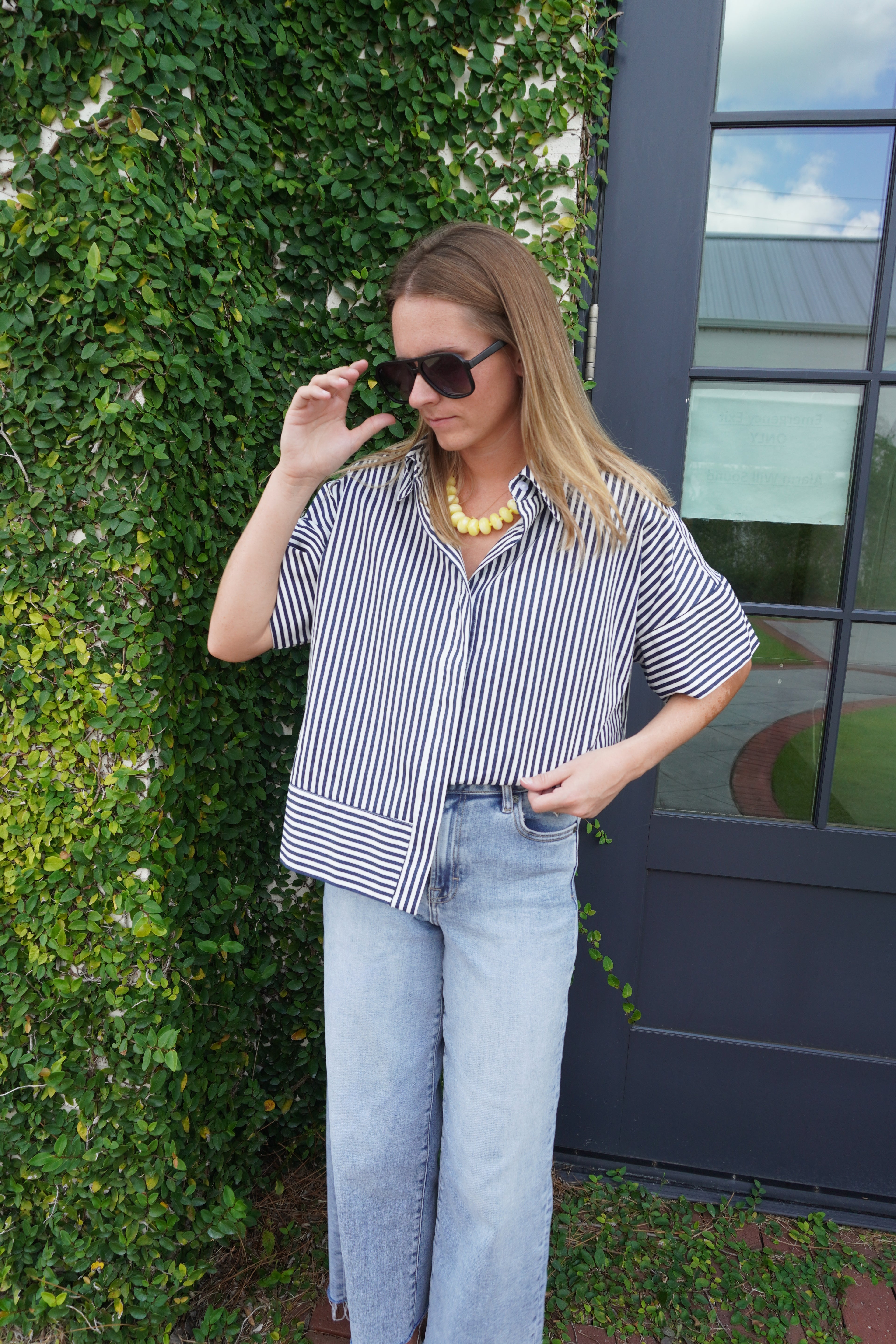 Woman wearing a navy and white striped short sleeve button-down top with light wash wide leg jeans from Anderson Ave Boutique