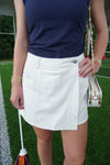 Person wearing a white skirt and blue top on a grassy field
