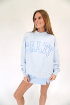 Light blue mock neck sweatshirt with “SALTY” graphic lettering and relaxed oversized fit