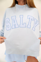 Soft blue mock neck sweatshirt with bold SALTY lettering and relaxed casual silhouette.