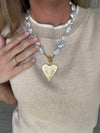 Necklace with a gold heart pendant worn by a person