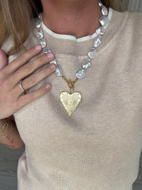 Necklace with a gold heart pendant worn by a person