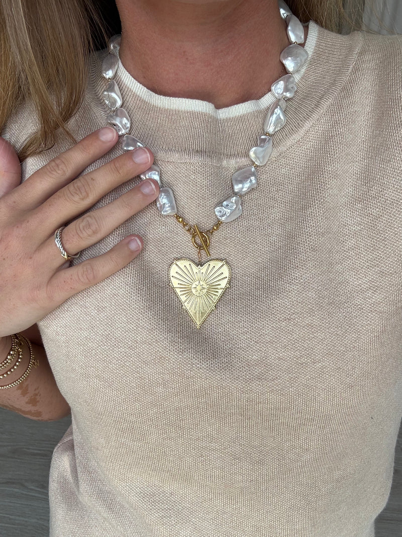Necklace with a gold heart pendant worn by a person