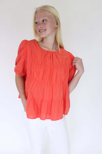 Sunset Breeze Tiered Babydoll Top - Coral Orange hand on shoulder 