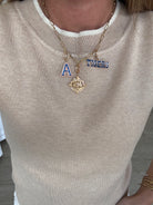 Necklace with 'A' and 'Tigers' pendant on a beige sweater