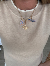 Necklace with 'A' and 'Tigers' pendant on a beige sweater