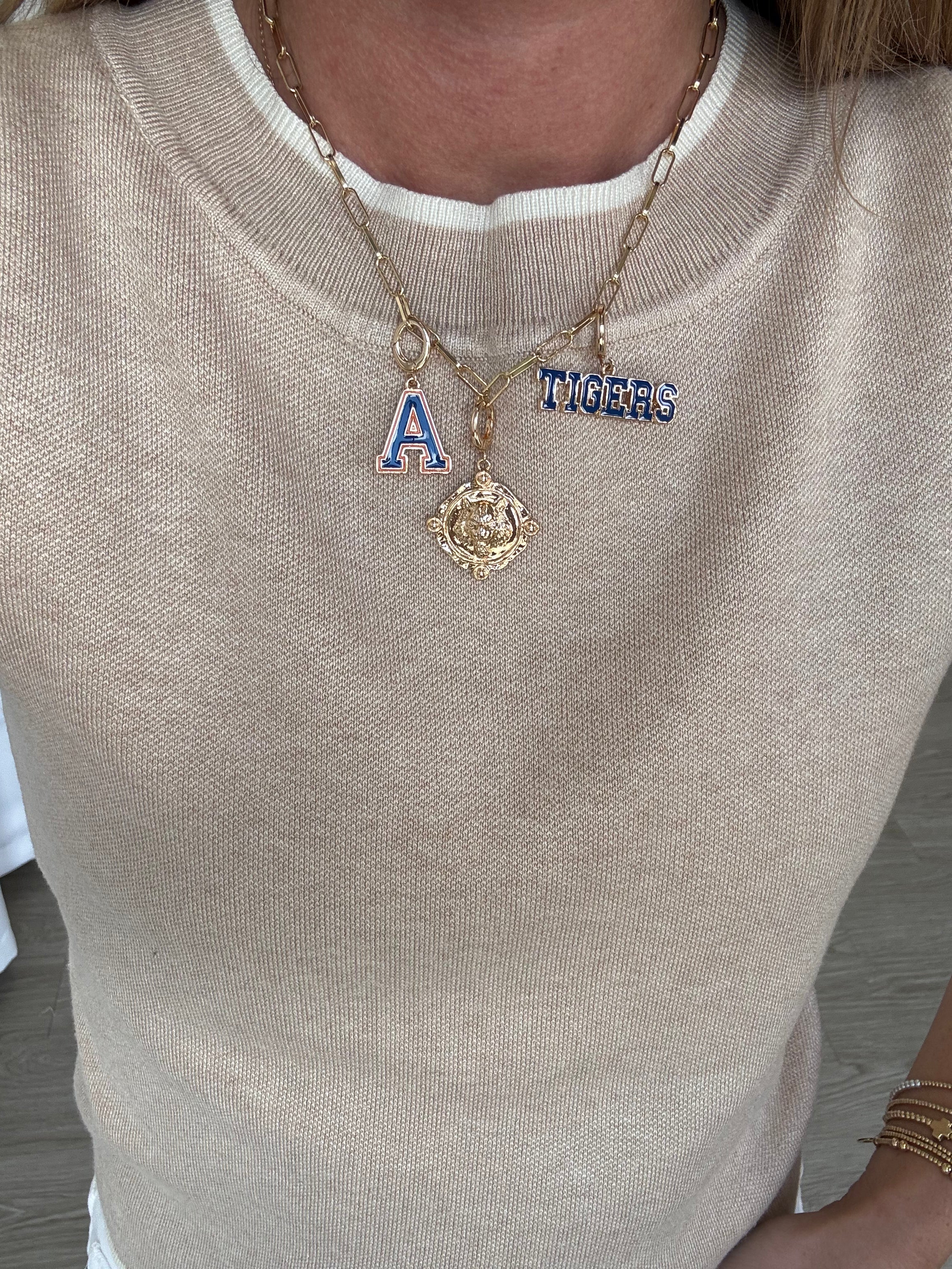 Necklace with 'A' and 'Tigers' pendant on a beige sweater