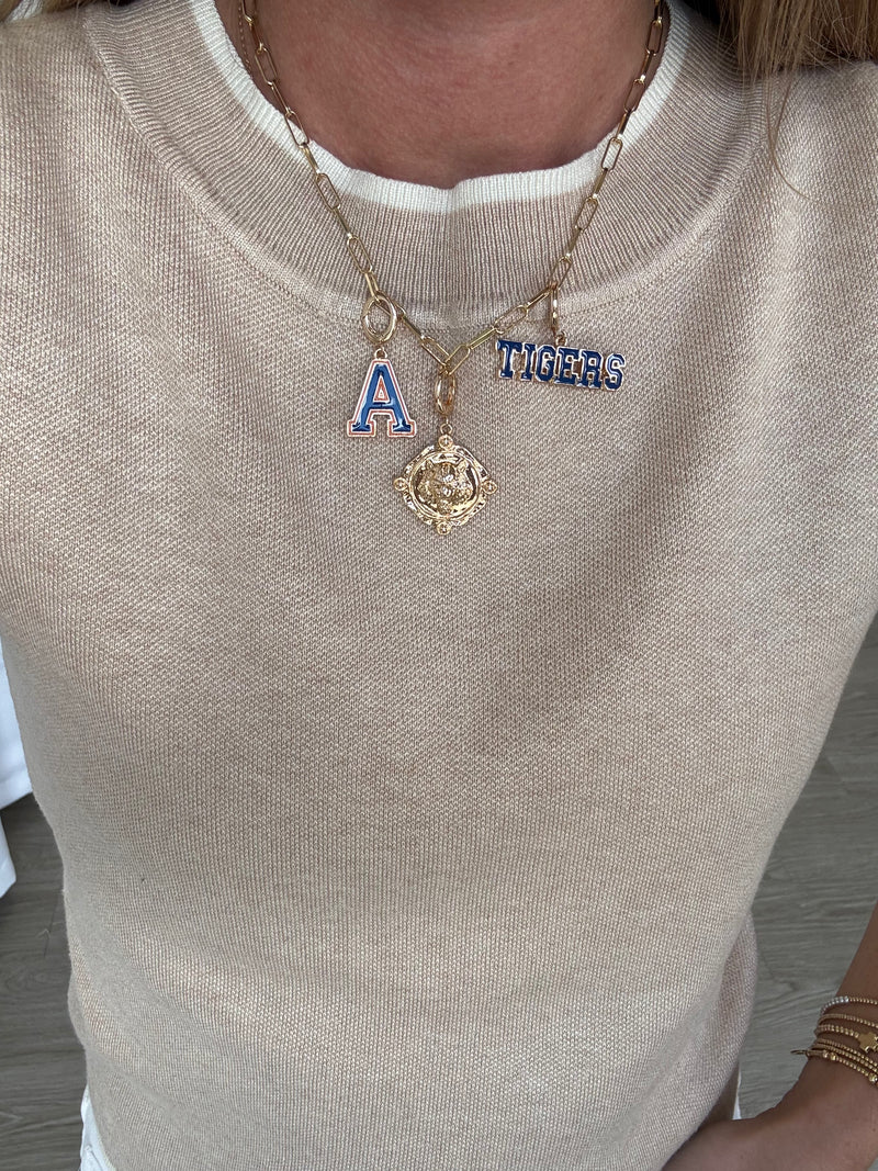 Necklace with 'A' and 'Tigers' pendant on a beige sweater