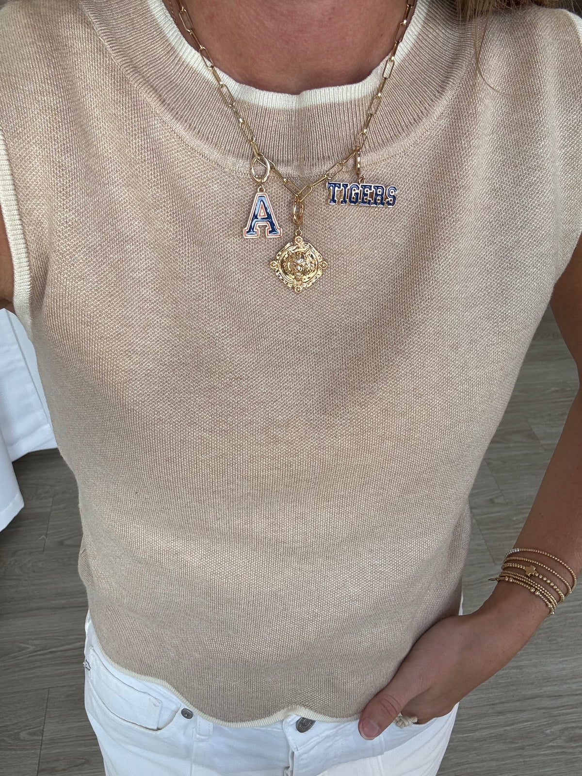 Person wearing a beige sleeveless top with visible jewelry including necklaces and bracelets.