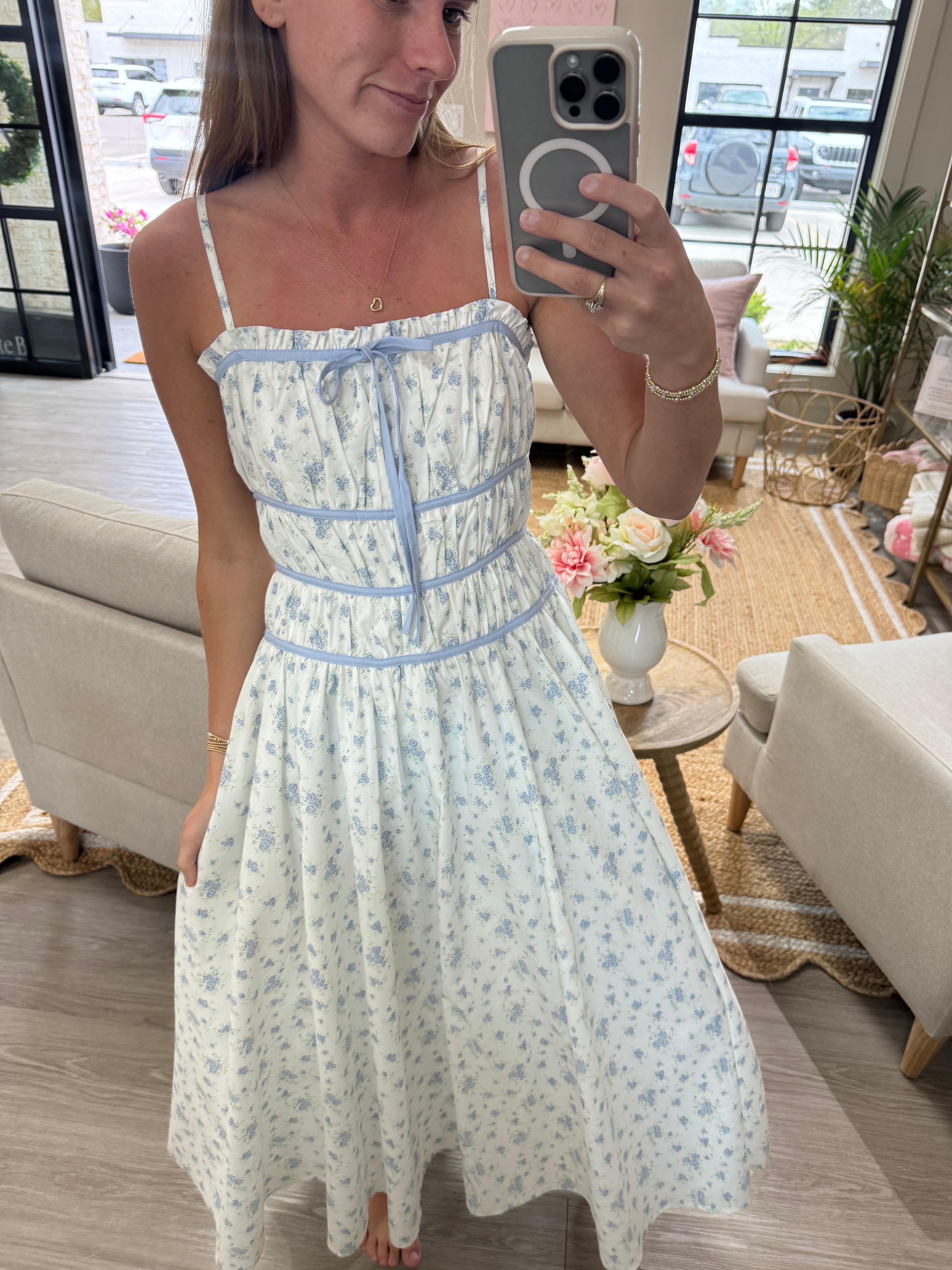 White and blue floral midi dress with adjustable straps, smocked bodice, and feminine flowy silhouette.