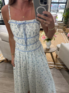 White floral sundress with blue print, spaghetti straps, and flattering gathered waist.