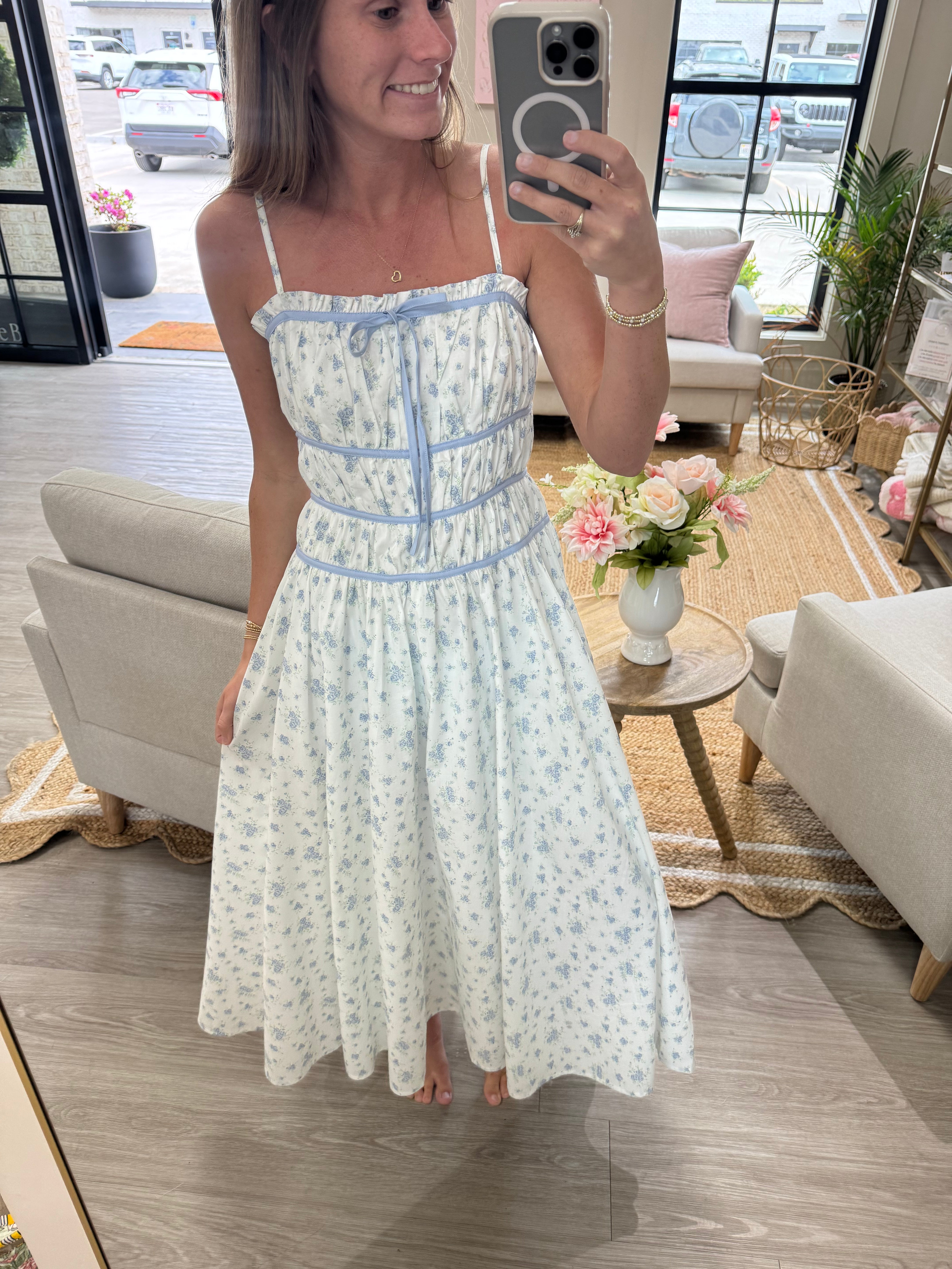 Feminine white and blue floral dress with adjustable straps and flowy skirt for spring and summer.