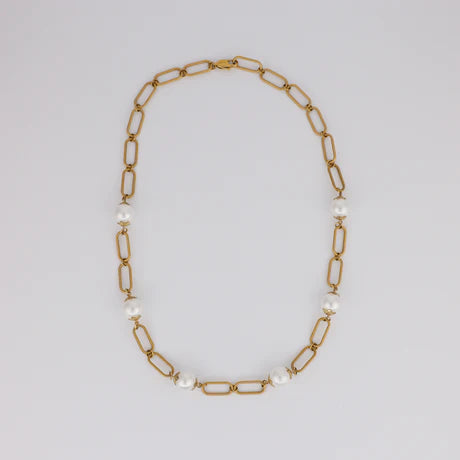 Gold chain necklace with pearls on a light gray background