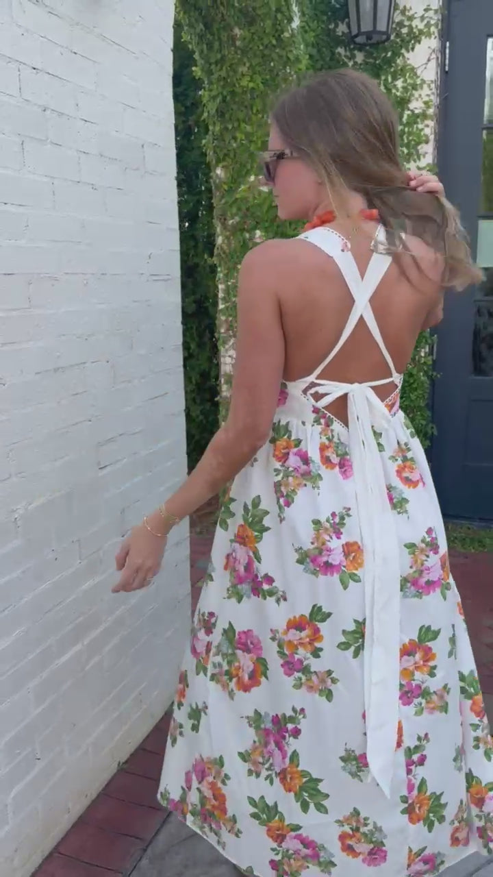 Spring floral midi dress with open back and tie detail photographed by greenery wall